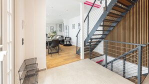Un interior moderno con una escalera, suelo de madera y una zona de comedor.