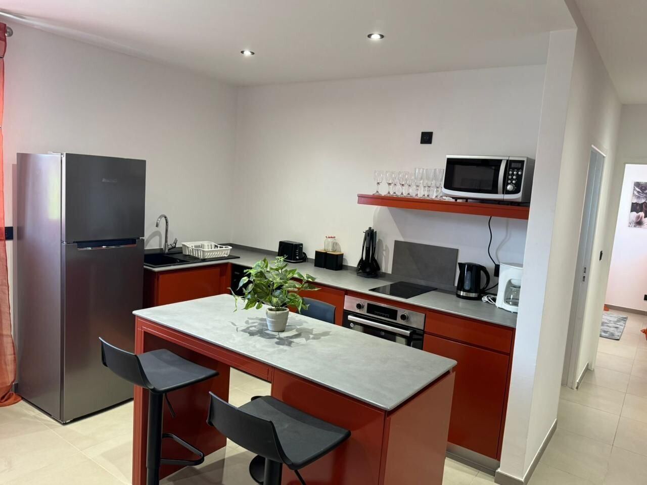 A compact kitchen with a refrigerator, microwave, sink, and a small dining area with two chairs.
