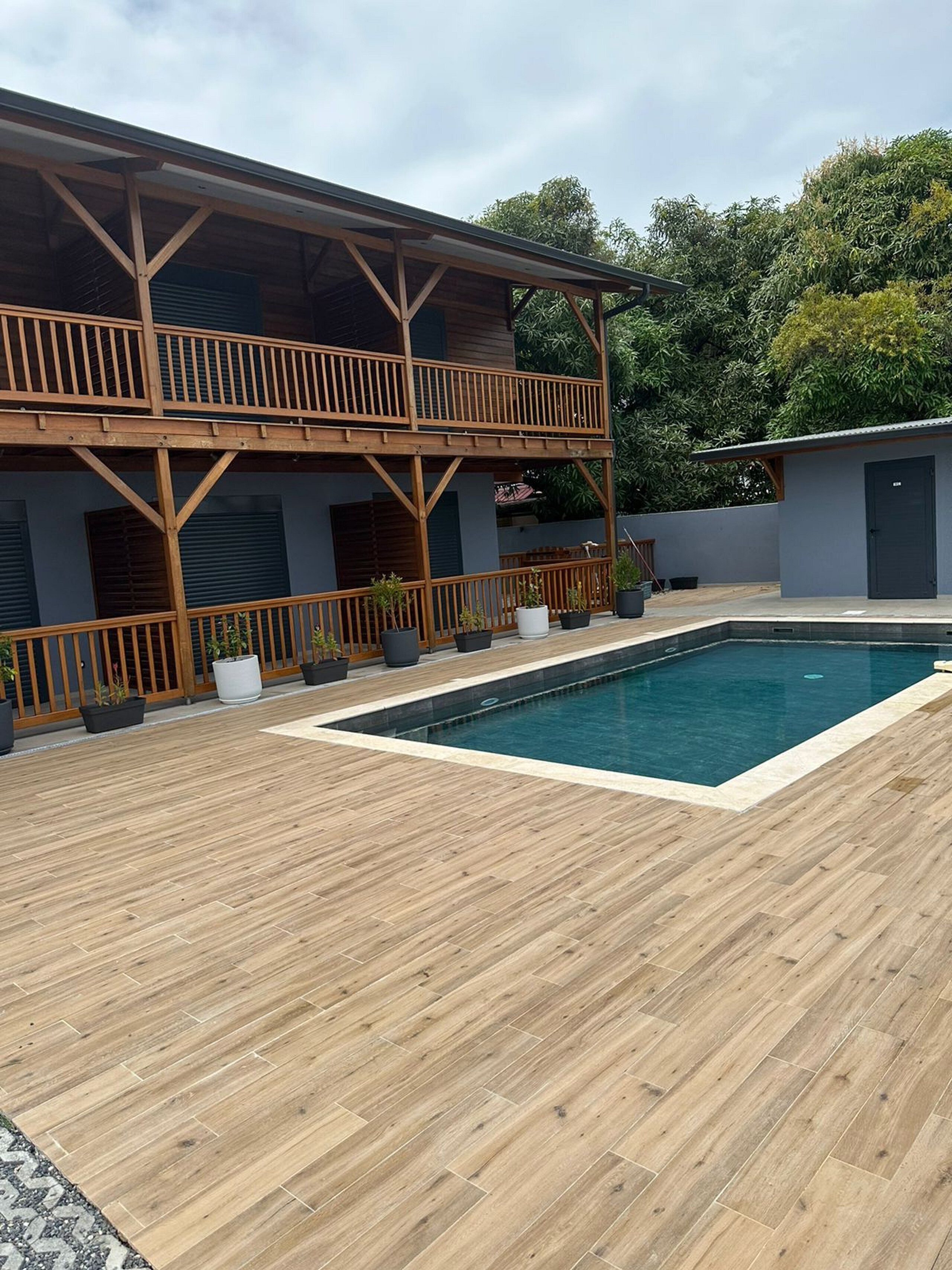 A two-story building with a wooden deck and a swimming pool.