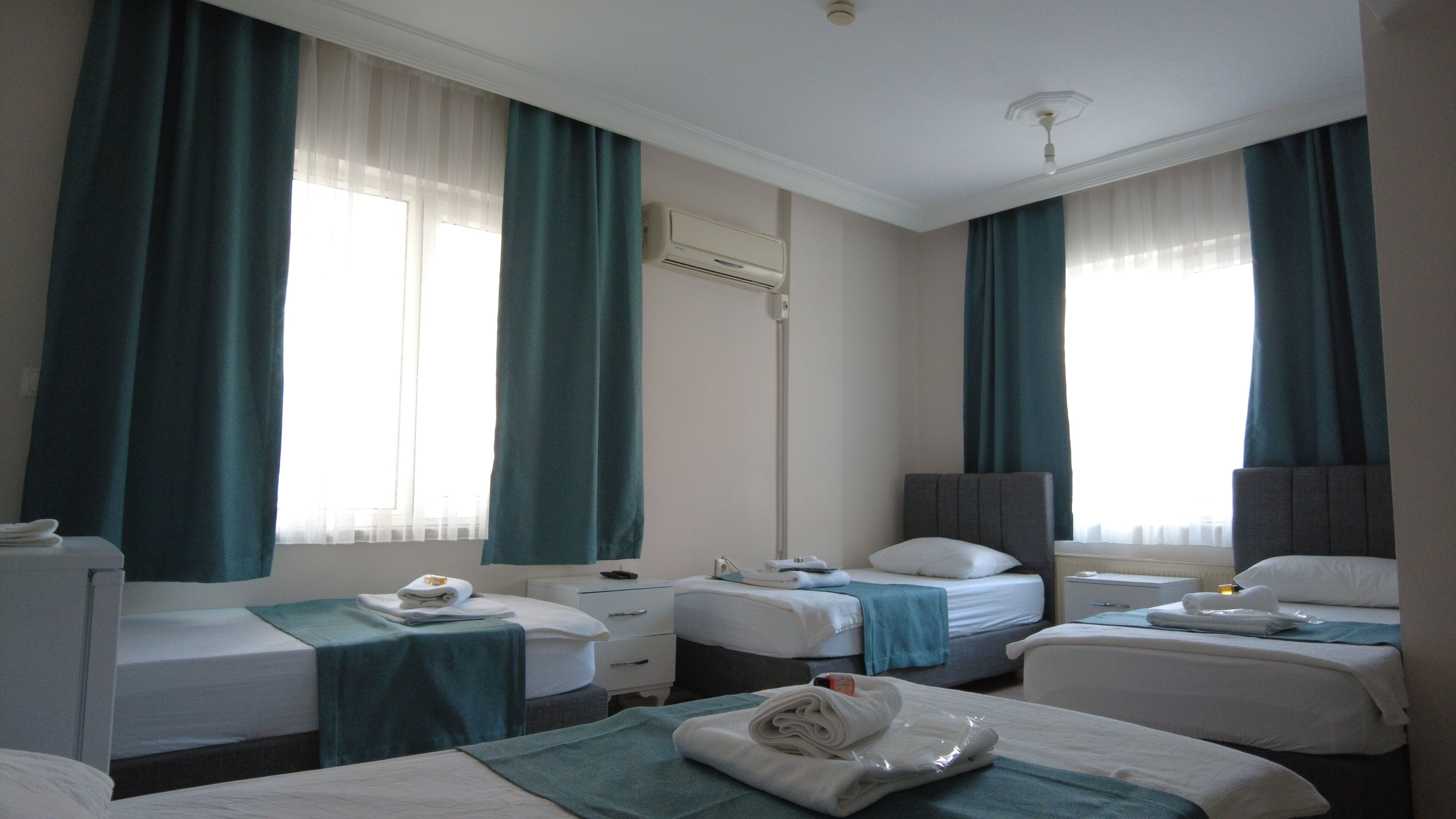 A hotel room with two single beds, a desk, a chair, and a standing lamp.