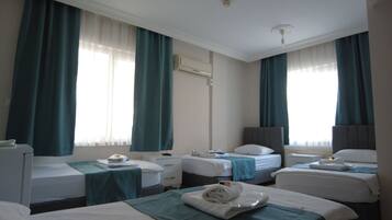 A hotel room with two single beds, a desk, a chair, and a standing lamp.