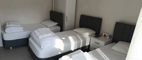 Une chambre d’hôtel avec deux lits simples, une petite table de chevet avec une lampe et une commode avec un téléphone et des articles de toilette.