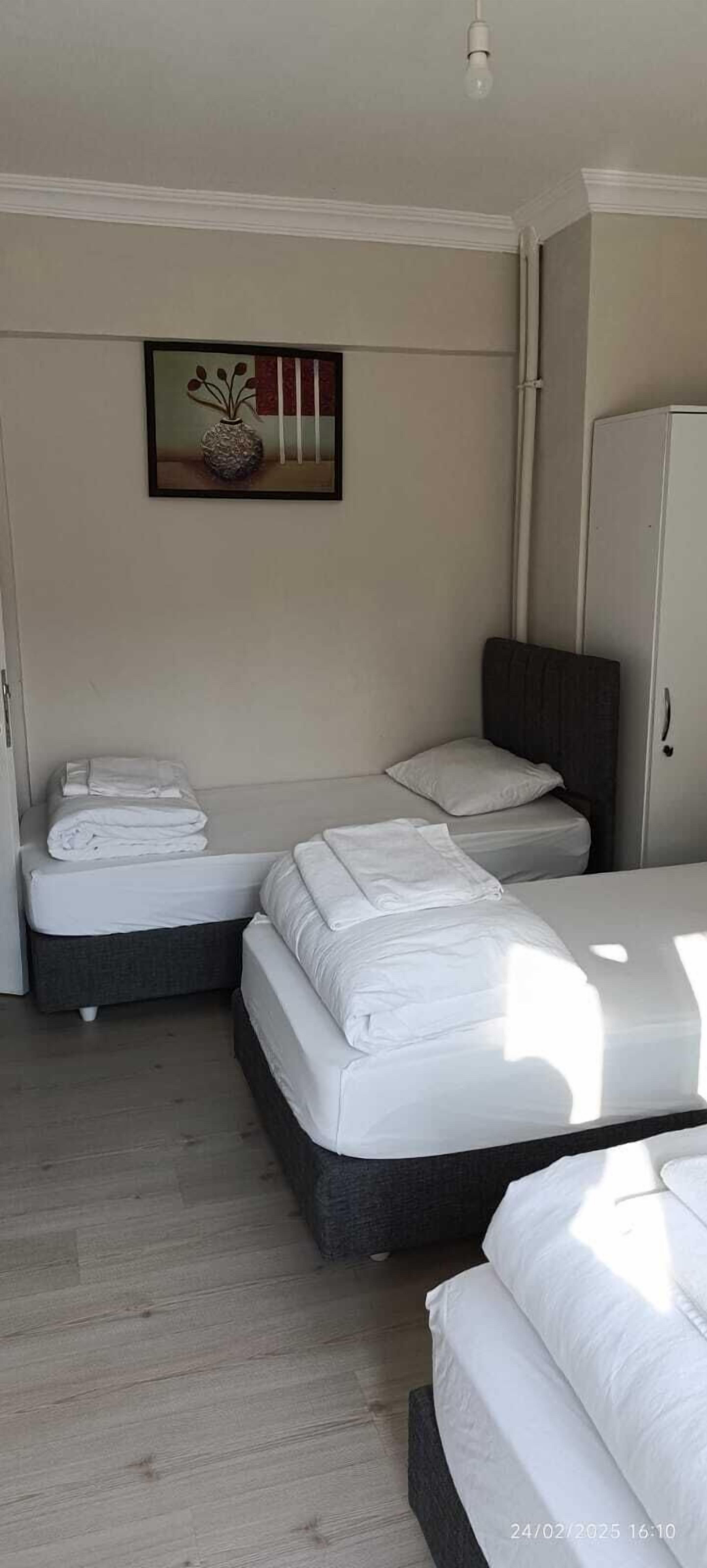 A room with two beds, a wardrobe, and a framed picture on the wall.