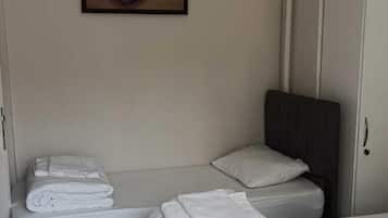 A room with two beds, a wardrobe, and a framed picture on the wall.