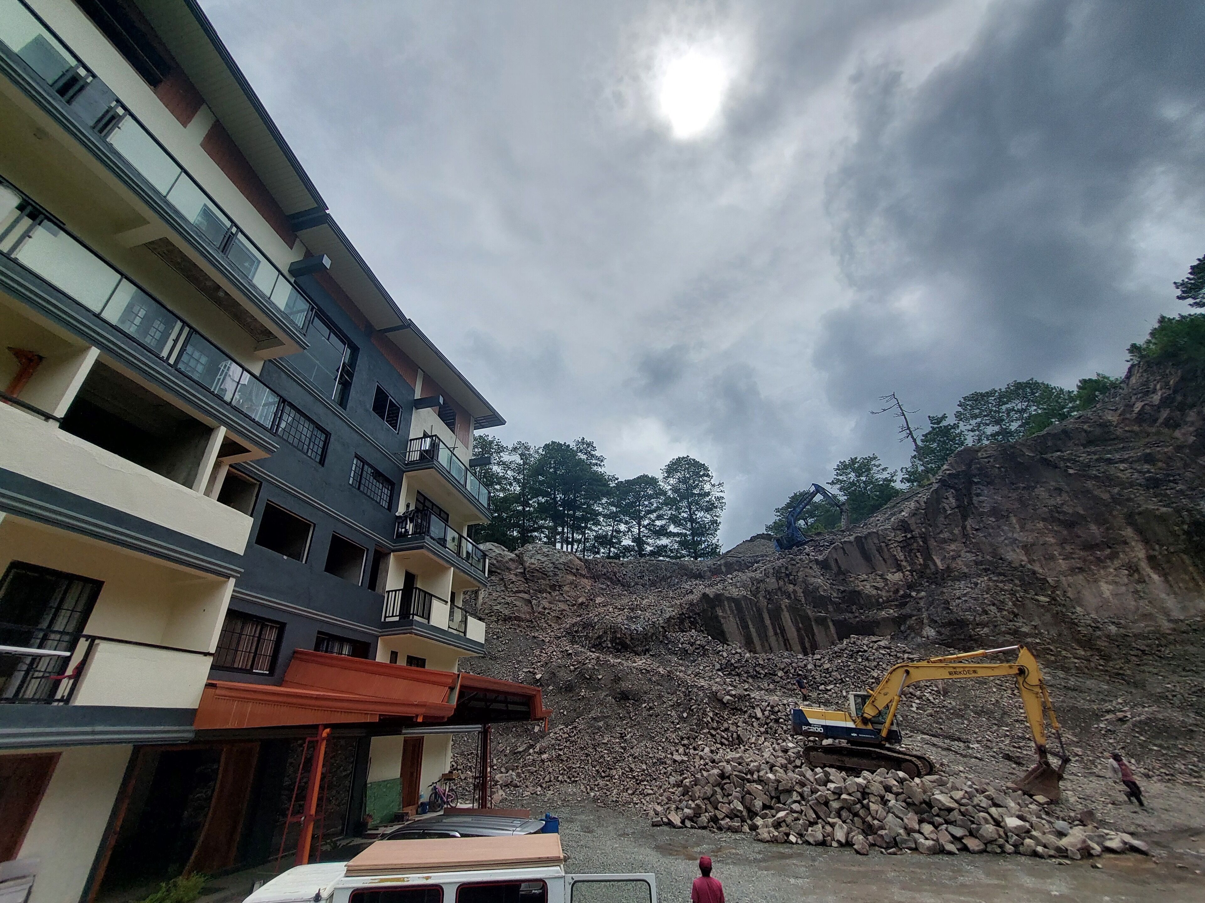 A multi-story building with balconies and a construction site with an excavator.