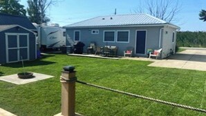 A residential area with a house, a trailer, and a well-maintained lawn. - Waterfront Cottage w/ boat dock

 (Blenheim)