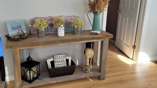 A wooden console table with decorative items including a sign reading "BEACH RULES: unwind DELAY", a framed picture, and small potted plants. - Waterfront Cottage w/ boat dock

 (Blenheim)