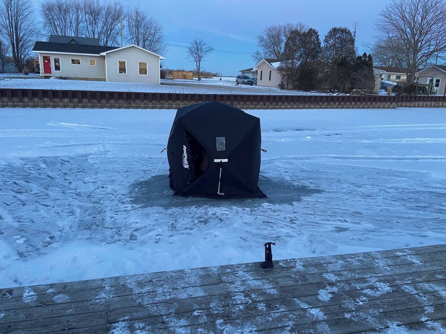 A black tent on a snow-covered ground with a wooden deck in the foreground.