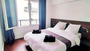 A hotel room with a bed, a window with curtains, and a balcony view.