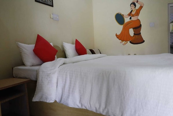 Une chambre d’hôtel avec un lit, des oreillers, une table de chevet et une fresque murale.