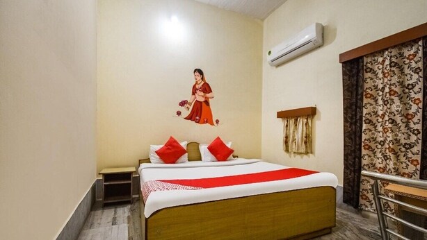 Ein Hotelzimmer mit Bett, Nachttisch, Wandklimaanlage und einer Wanddekoration.