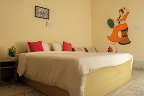 Habitación de hotel con una cama grande, una mesita de noche, una pequeña mesa con una planta y un mural en la pared.