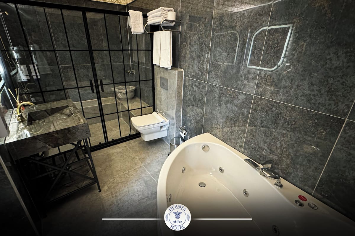 A modern bathroom with a glass-enclosed shower, a freestanding bathtub, and a toilet.