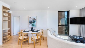 Un salon moderne avec une table de salle à manger ronde, des chaises en bois, un canapé et un téléviseur.