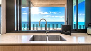 Une cuisine avec vue sur l’océan, un panneau indiquant un bar à cocktails et un design moderne.