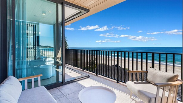 Un balcon moderne avec une porte vitrée donnant sur une pièce, une table ronde et un canapé.