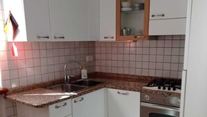 Ett kompakt kök med vita skåp, en bänkskiva i granit, en diskho i rostfritt stål och en inbyggd ugn.