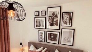 Una camera da letto con un letto grande, molti cuscini, un comodino con una lampada e un muro decorato con quadri.