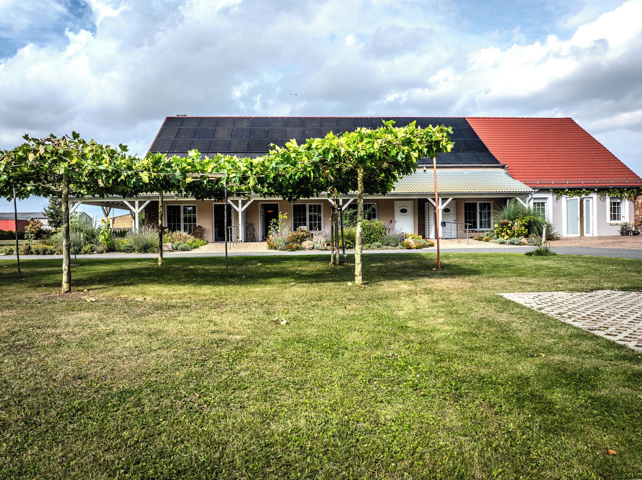 A building with a covered outdoor area, a red roof, and a grassy lawn.