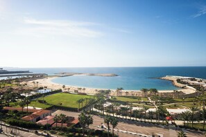 Un resort costero con playa, palmeras y una vista despejada del océano.
