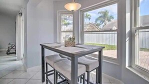 A dining area with a table and chairs, large windows, and a view of a backyard.