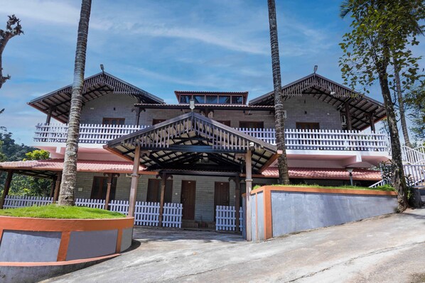 A two-story building with a balcony and a covered entrance. - Treebo River View (Madikeri)