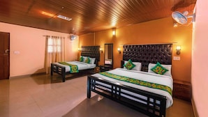 Quarto de hotel com duas camas, teto de madeira e luminárias fixadas na parede.