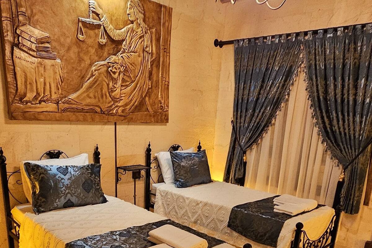A room with two beds, a large painting, and a chandelier.