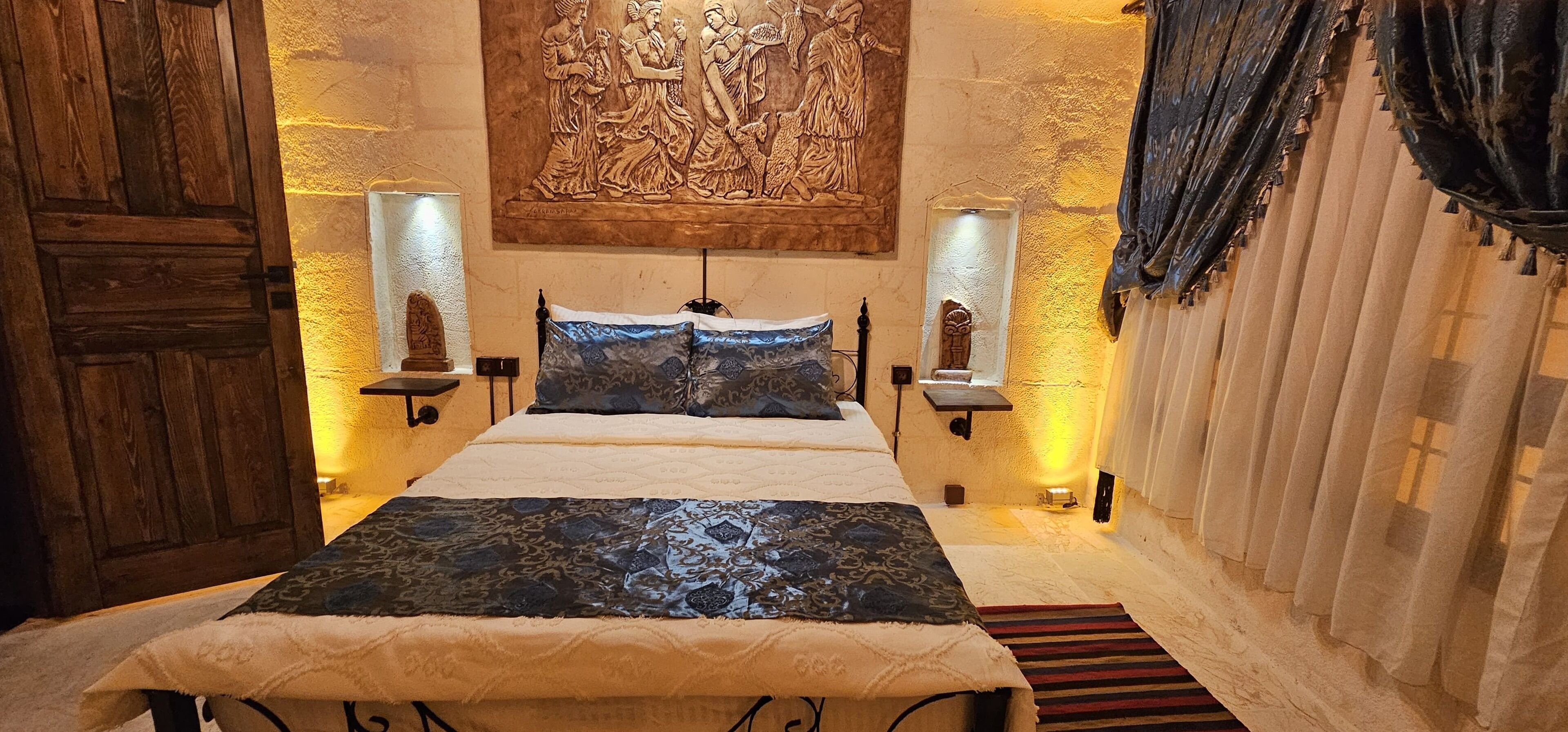Un dormitorio con una cama grande, dos lámparas fijadas a la pared y un adorno mural.