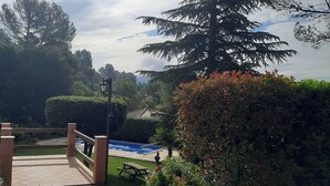Un pont de fusta que condueix a una zona de piscina envoltada de vegetació i arbres frondosos.