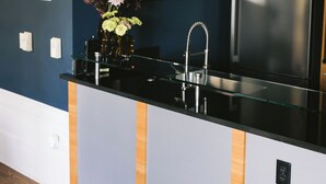 Eine moderne Küche mit schwarzem Arbeitsplatz, Edelstahlgeräten und einem Holzkorpus.