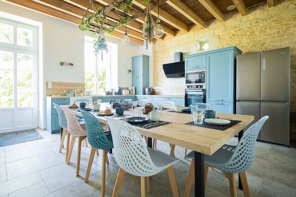 A modern kitchen with a wooden table, blue cabinets, and a stainless steel refrigerator.