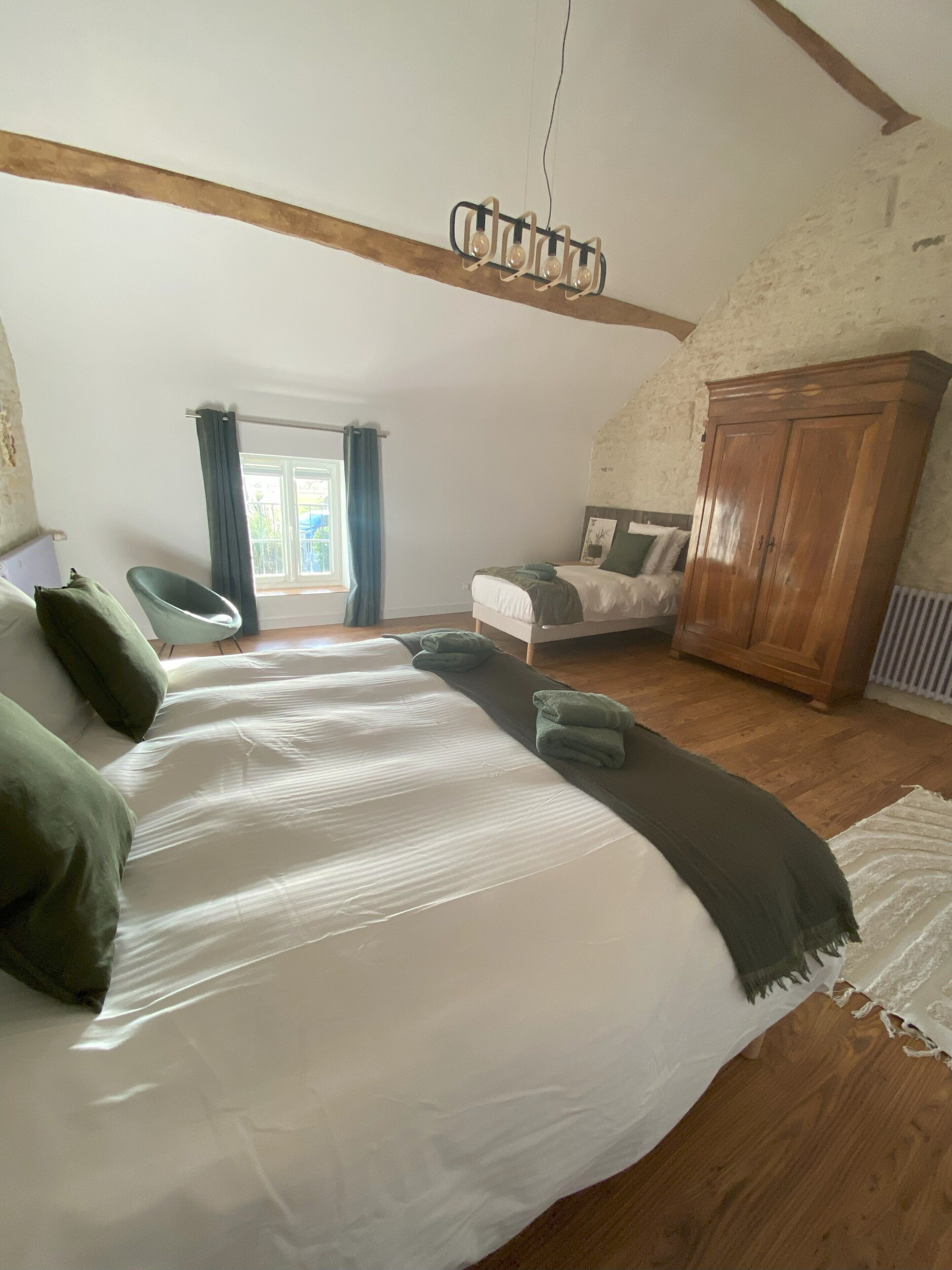 Une chambre avec un grand lit, une armoire en bois et une fenêtre avec des rideaux.