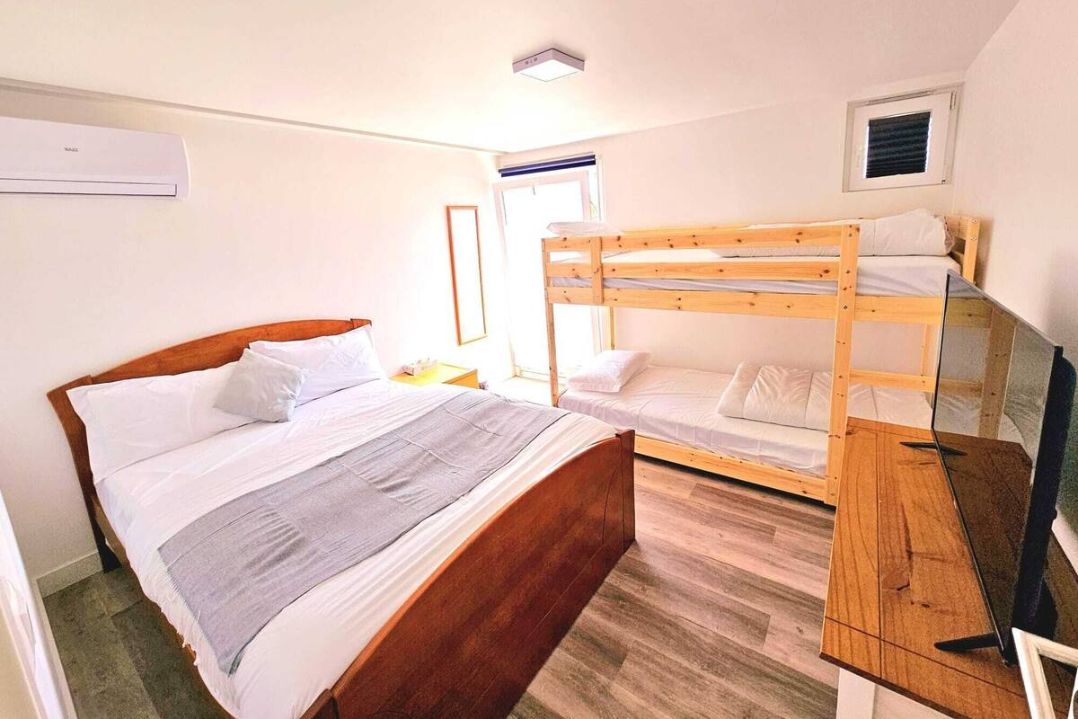 Ein Zimmer mit einem Holzbett, einem Einzelbett und einem Schreibtisch mit einem Laptop.