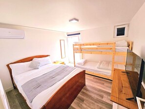 Ein Zimmer mit einem Holzbett, einem Einzelbett und einem Schreibtisch mit einem Laptop.