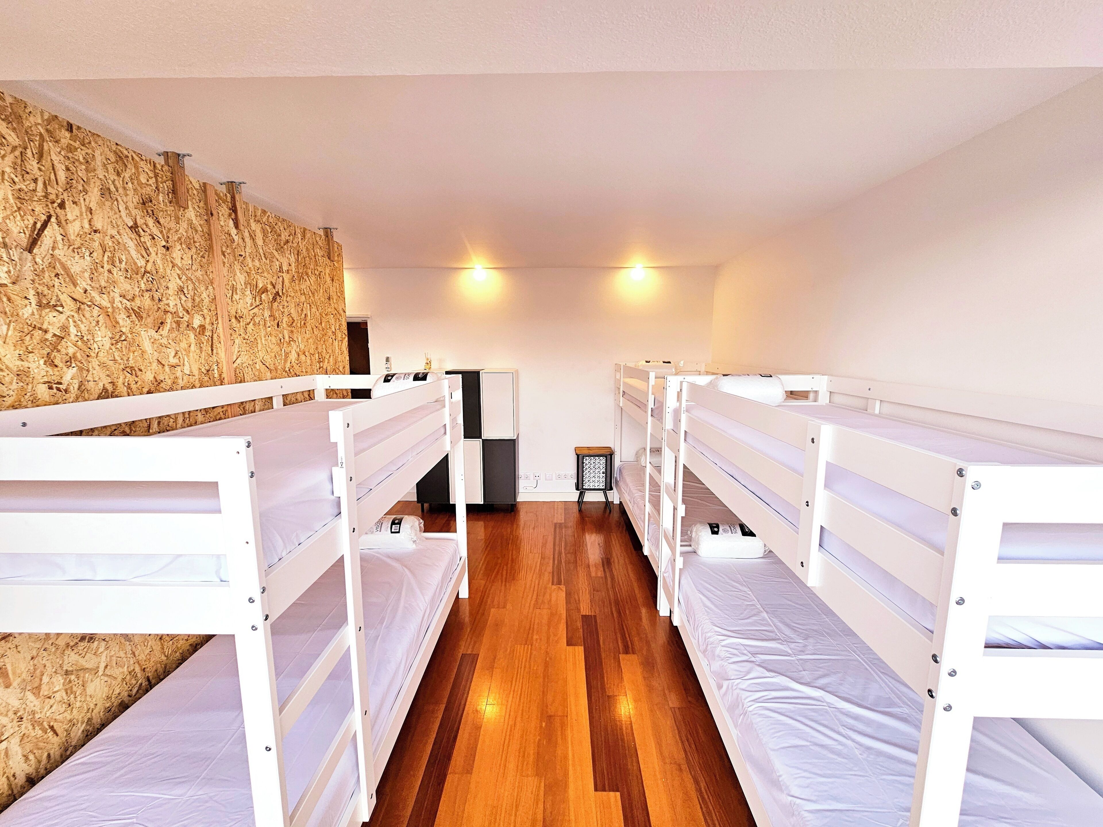 Un dormitorio con literas, suelo de madera y una pared con superficie texturizada.