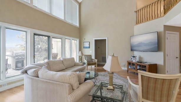 A spacious living room with a large sofa, a glass coffee table, and a television.