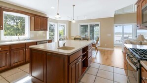 Une cuisine spacieuse avec des meubles en bois, un grand îlot central et un four encastré.