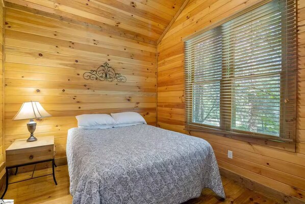 Upstairs bedroom featuring wood paneling throughout and ceiling fan.
