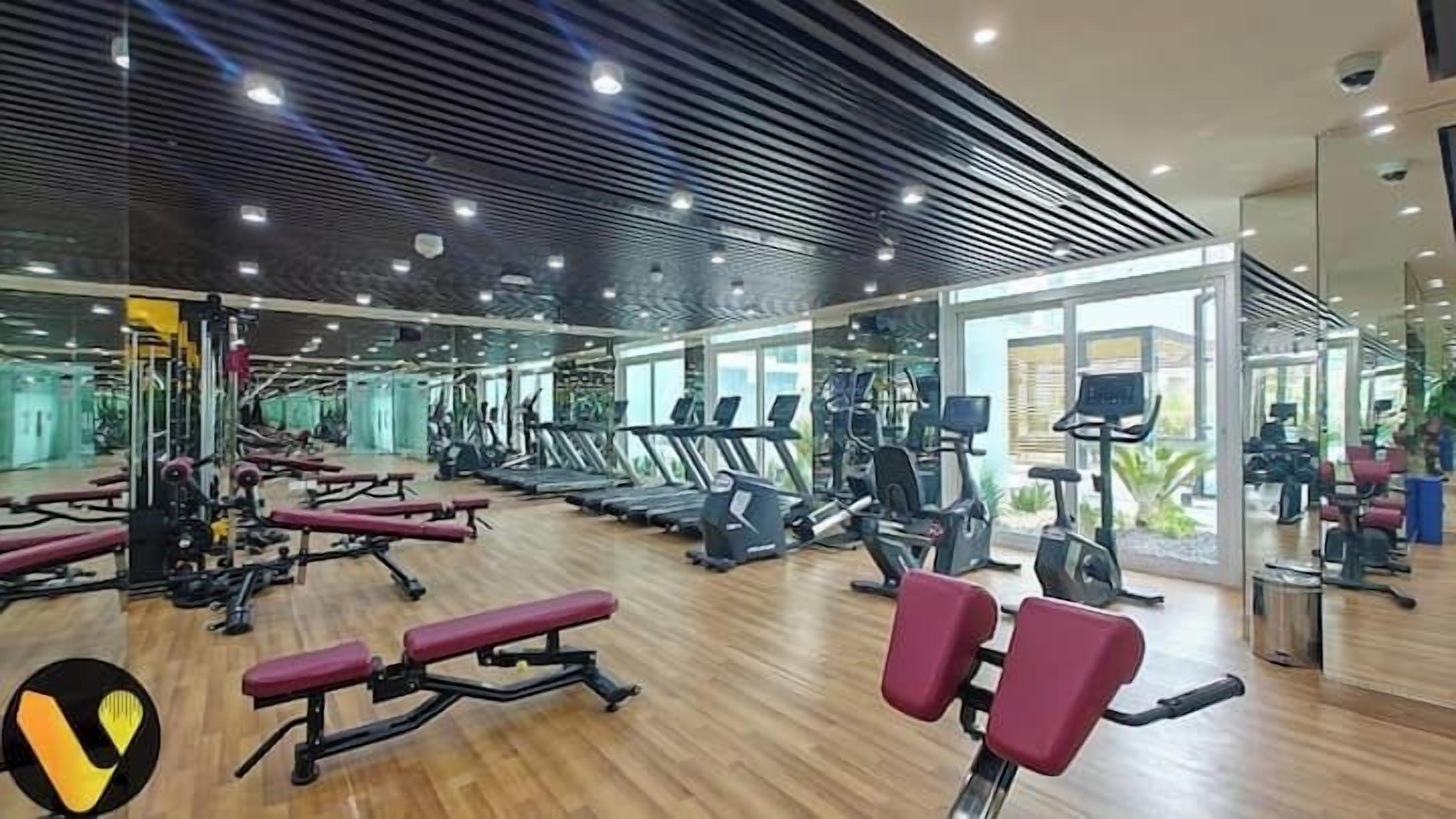 A gym with treadmills, weight machines, and a mirrored wall.