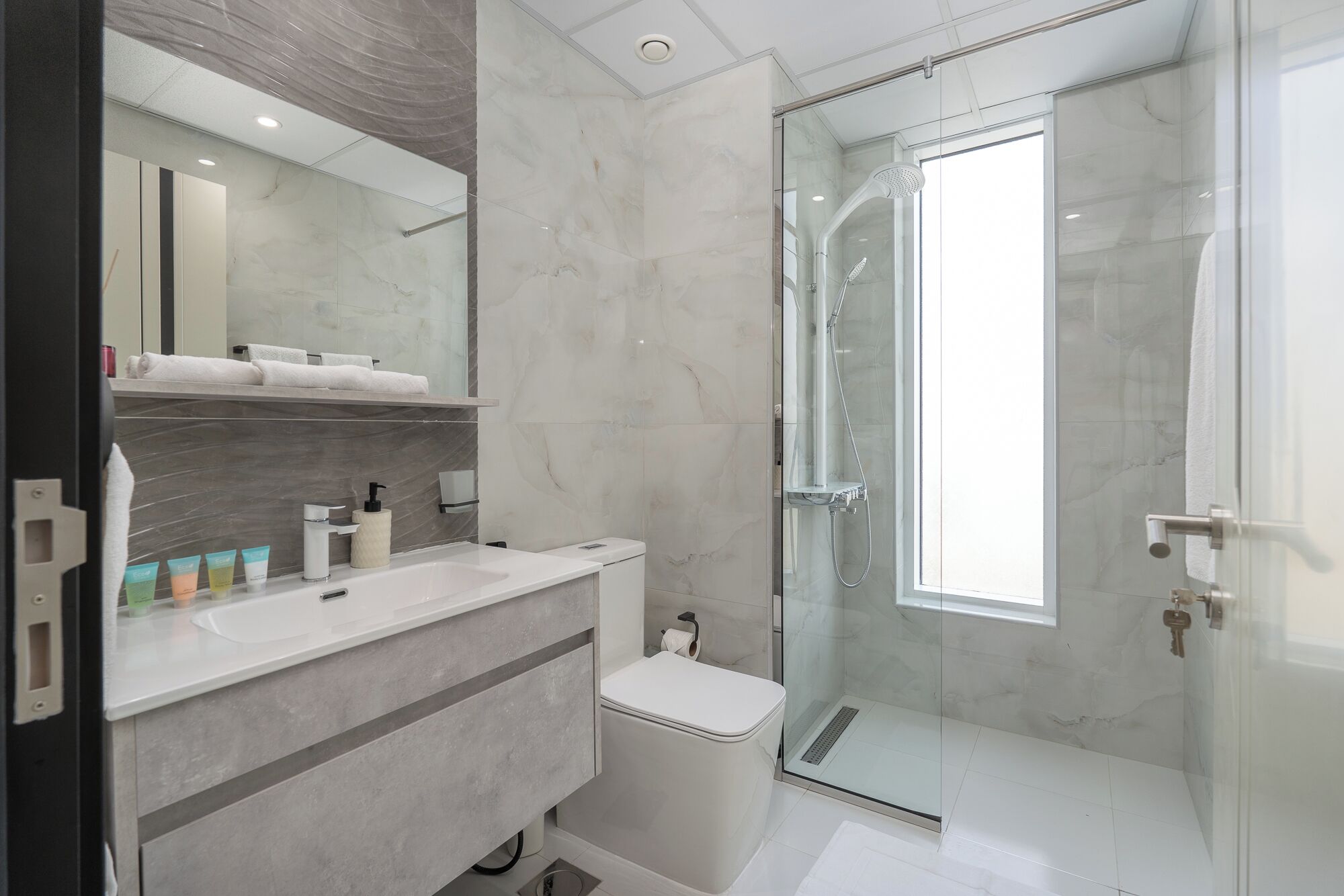 A modern bathroom with a glass-enclosed shower, a vanity with a mirror, and a toilet.