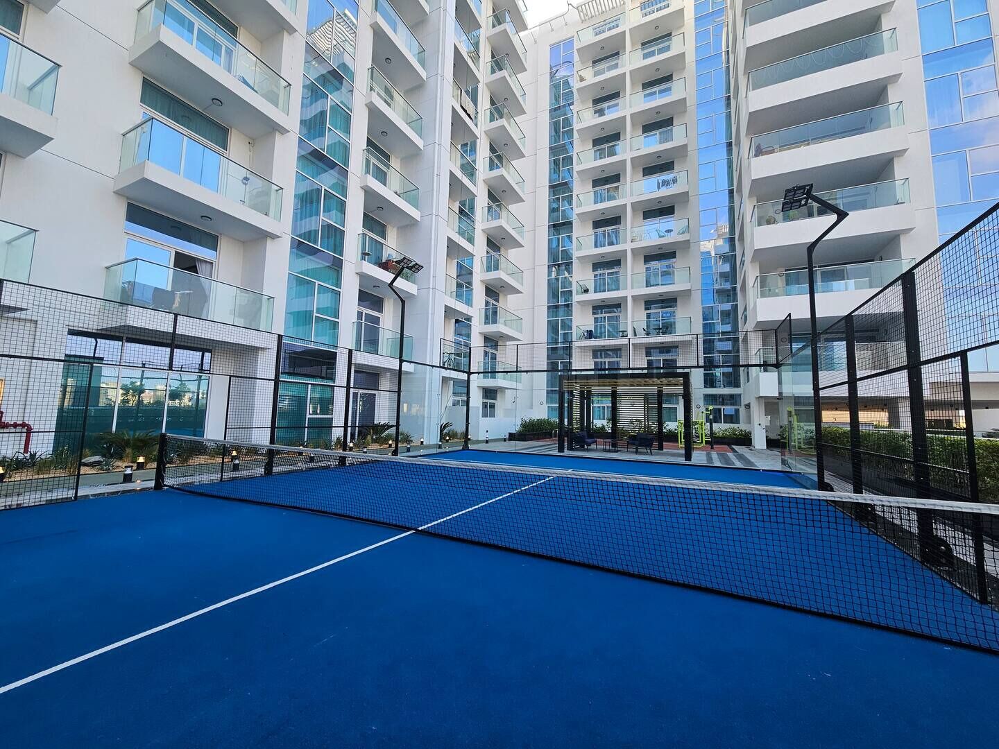 Un edificio de varios pisos con una cancha de tenis al frente.