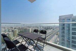 Un balcón con mesa y sillas, con vista a la ciudad.