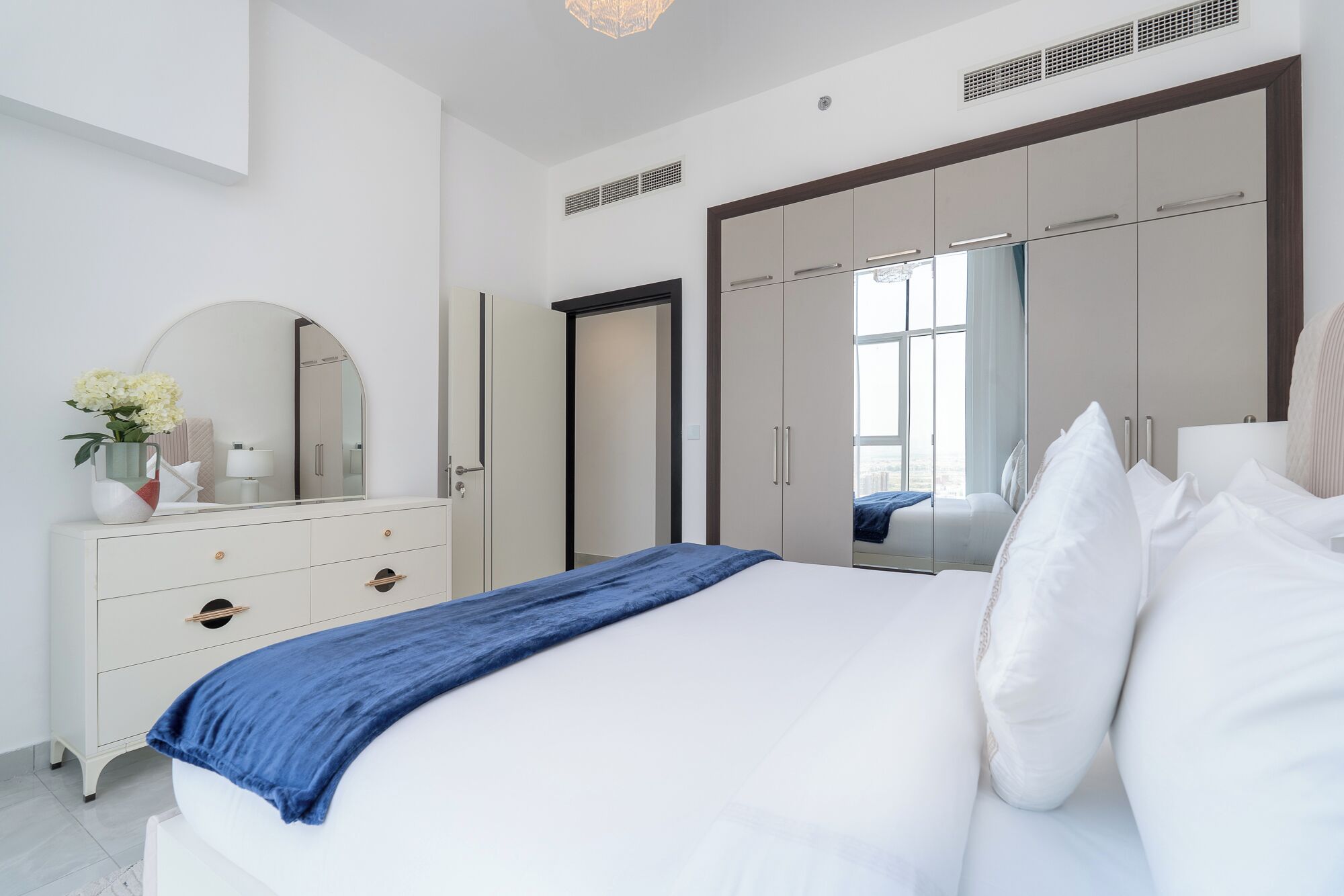 Une chambre à coucher moderne avec un grand lit, une commode, un miroir et une armoire.
