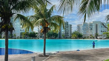 A swimming pool area with palm trees and a building in the background.