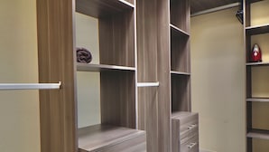 A walk-in closet with wooden shelving, drawers, and a hanging rod.