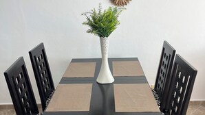 Een eettafel met een witte vaas en groene planten, omringd door zwarte stoelen met luipaardprint kussens.