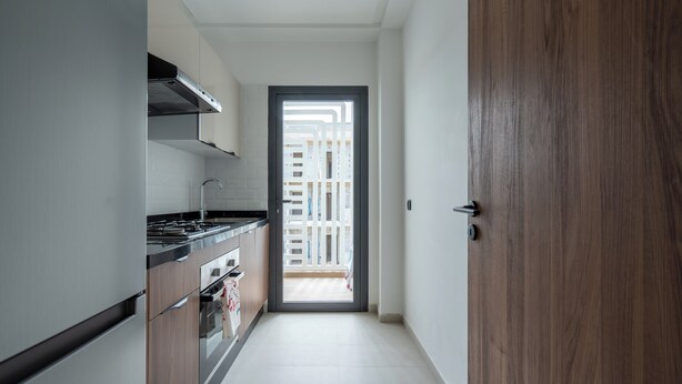 Et moderne køkken med rustfrit stål hvidevarer, en trädør og udsigt til en balkon.