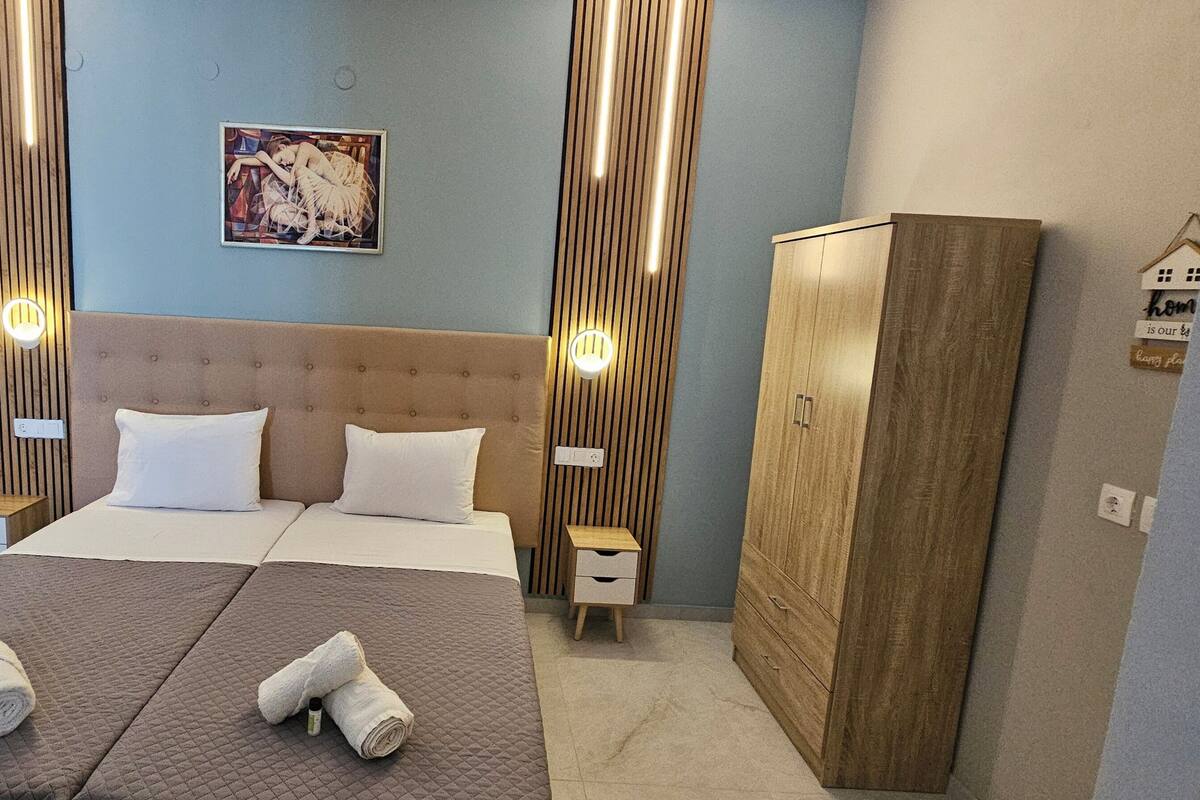 A hotel room with a large bed, two bedside tables, a wardrobe, and a wall-mounted artwork.