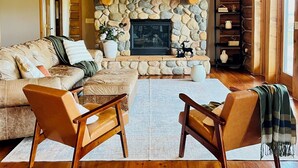 A cozy log cabin interior with a stone fireplace, wooden furniture, and a stone wall. - Foote Creek Lodge (Aberdeen)